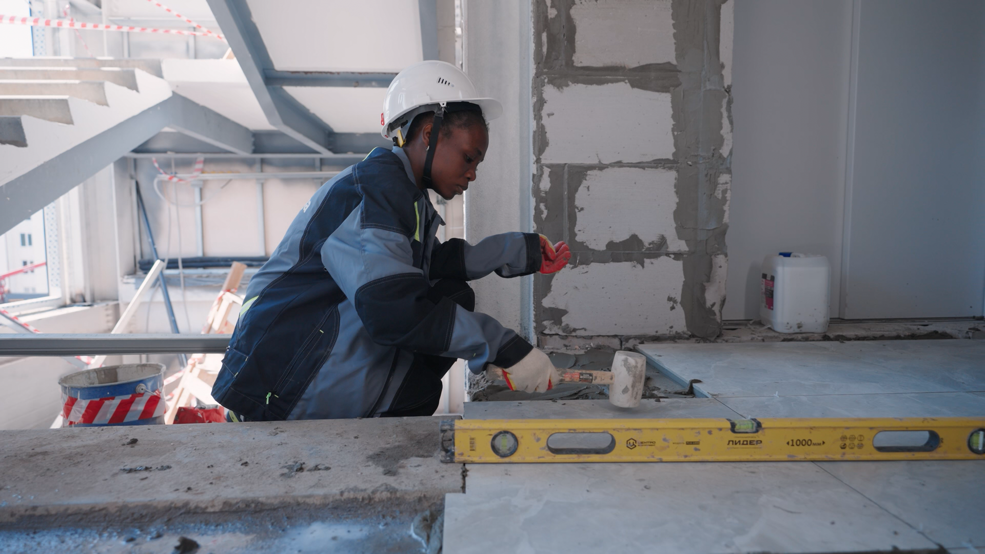 Женщина-маляр аккуратно наносит финишную шпаклевку на стену в новостройке